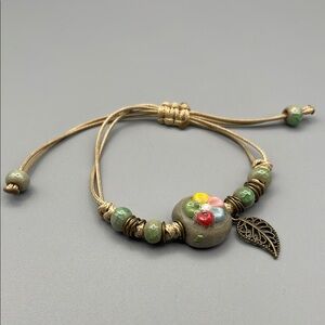 Artisan Floral Beaded Bracelet with Leaf Charm. Adjustable pull cord.